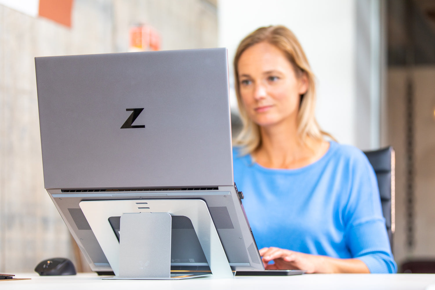 Vrouw achter stijlvolle OviStand Max laptopstandaard met Windows laptop