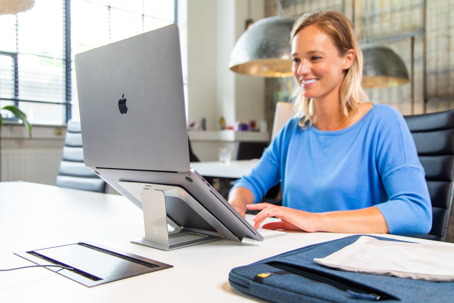 Vrouw werkt ergonomisch achter laptop op OviStand laptopstandaard