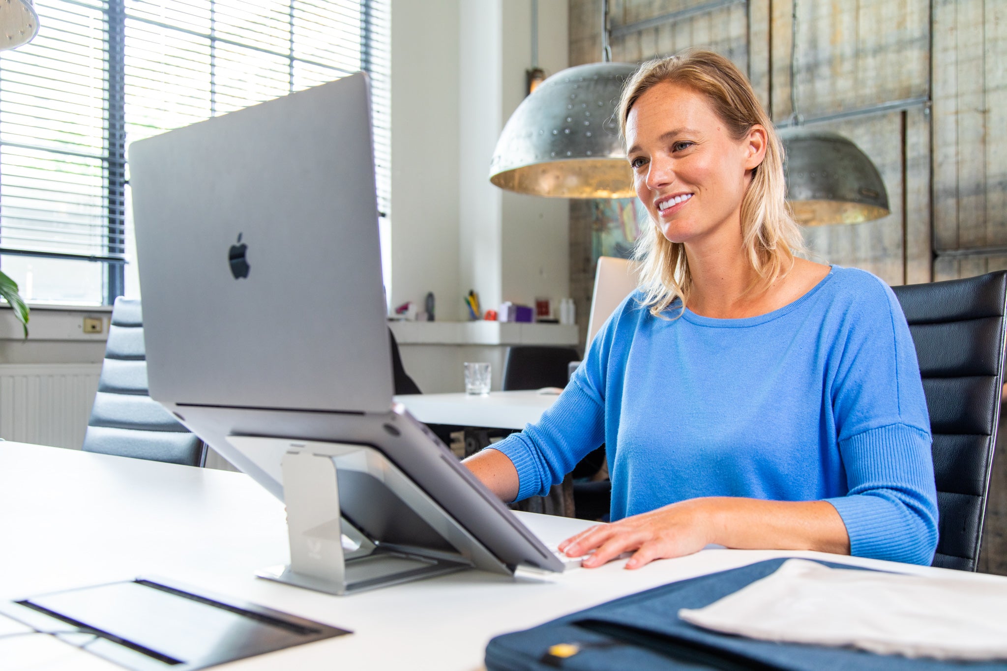 Vrouw werkt ergonomisch achter laptop op lichte, compacte, stijlvolle OviStand standaard